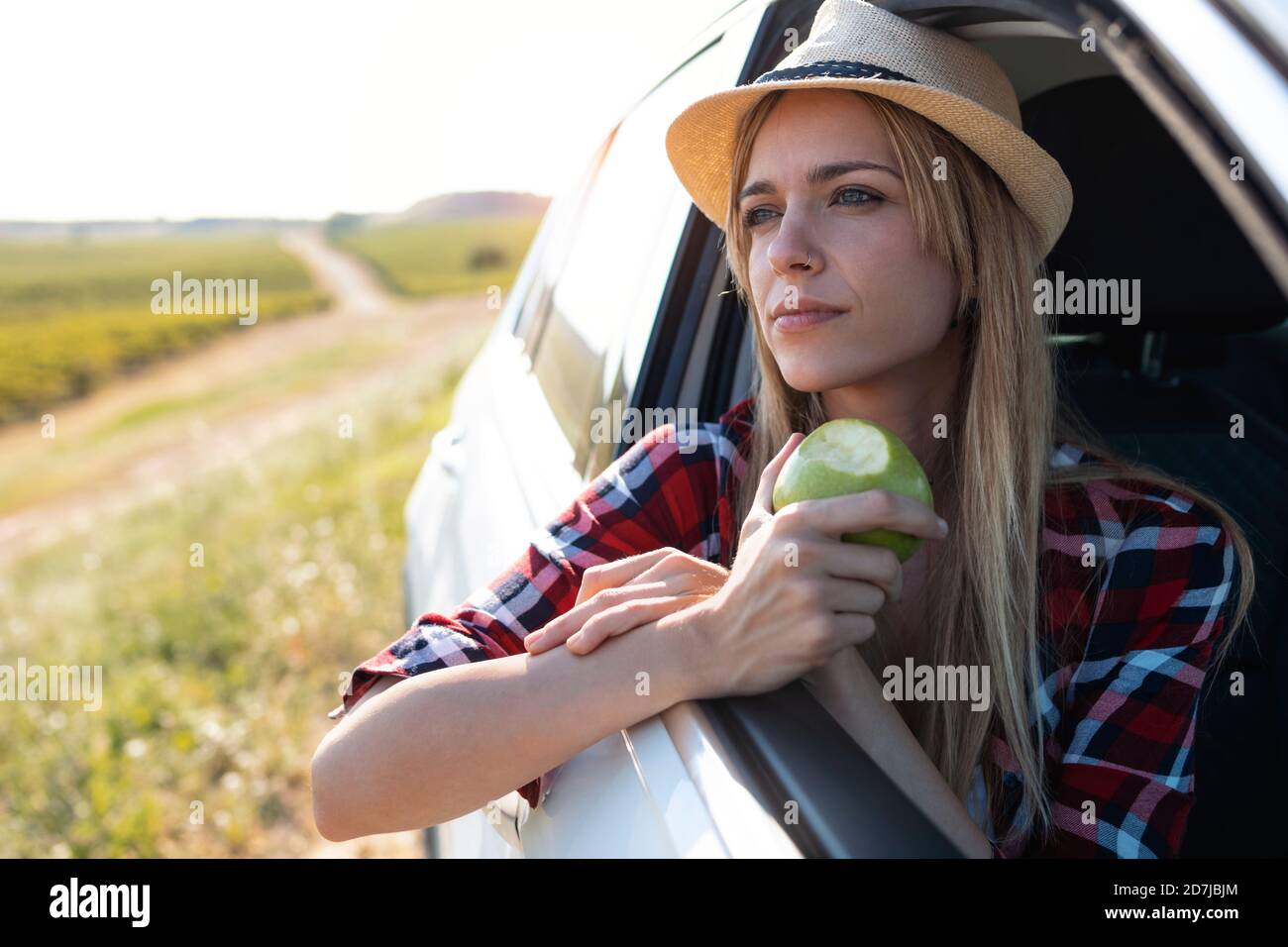 Giovane donna che mangia frutta mentre si siede in auto Foto Stock