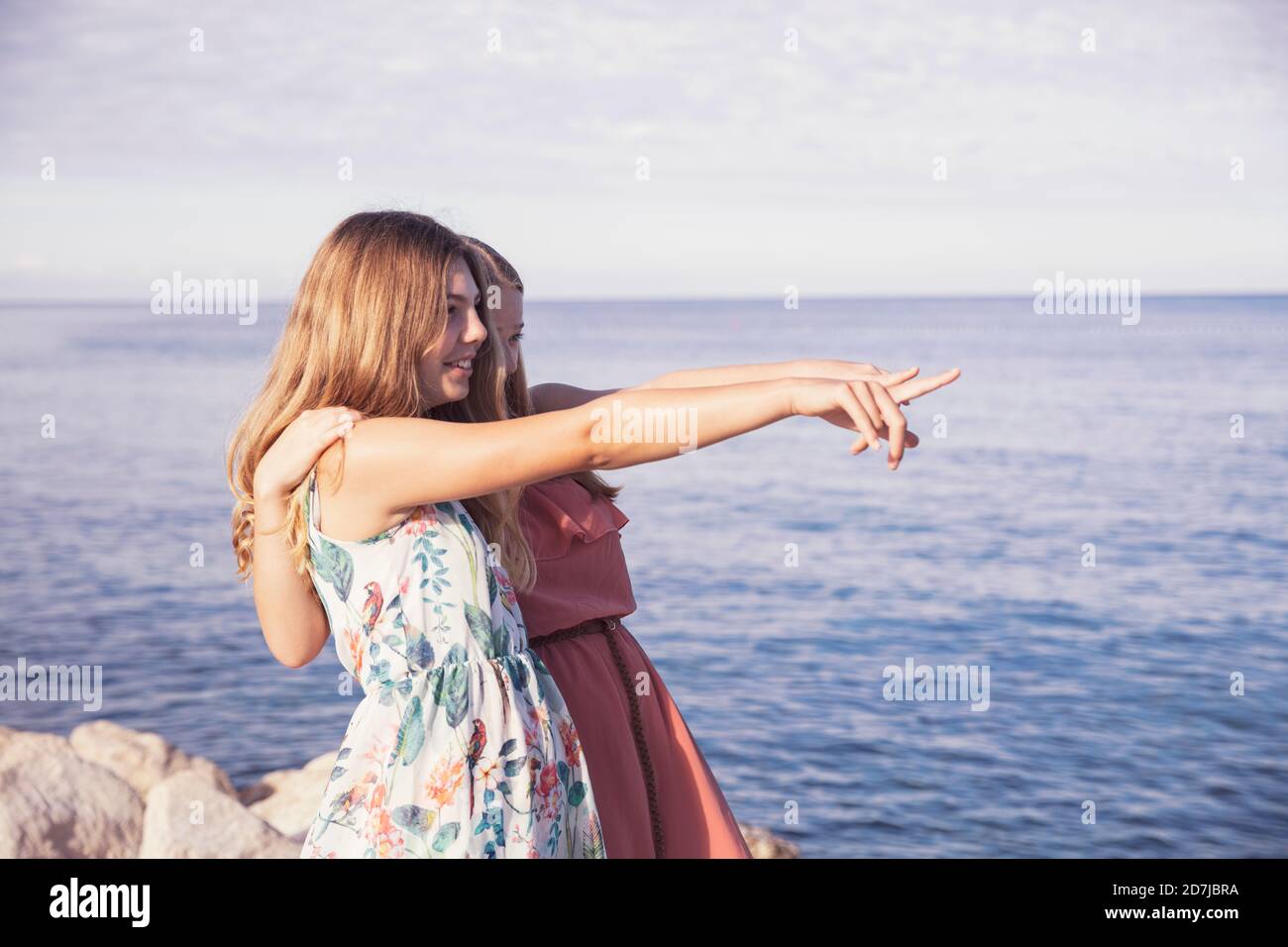 Amici che puntano al mare con le braccia intorno nella giornata di sole Foto Stock