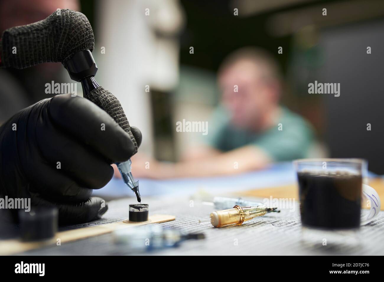 Mano di artista maschile immersione macchina tatuaggio in inchiostro su tabella Foto Stock