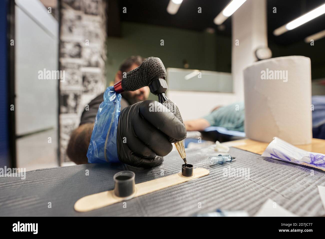 Primo piano di un artista maschile immersione macchina tatuaggio in inchiostro su tabella Foto Stock