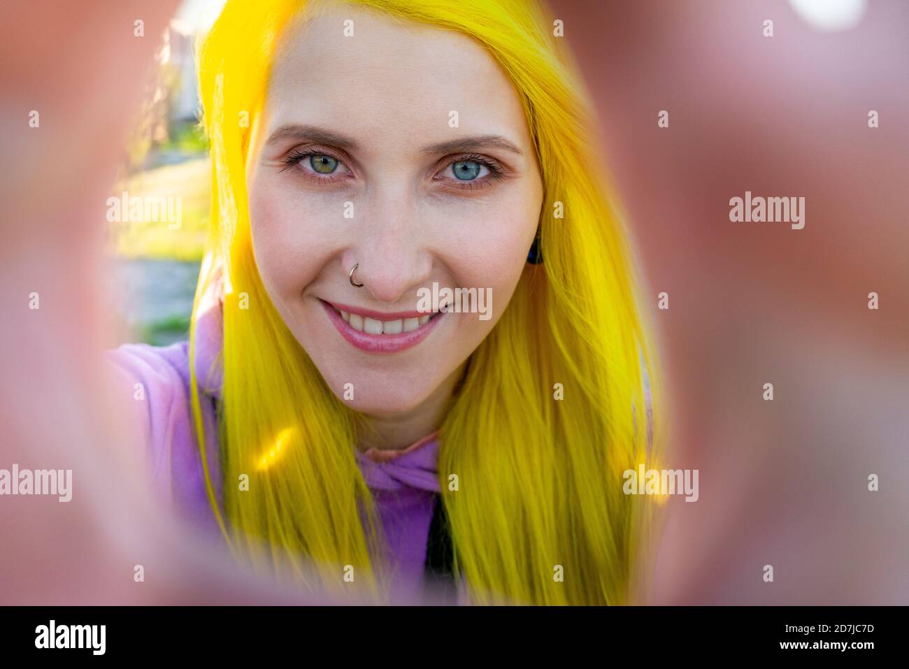 Hipster femmina sorridente mentre si trova all'aperto in giornata di sole Foto Stock