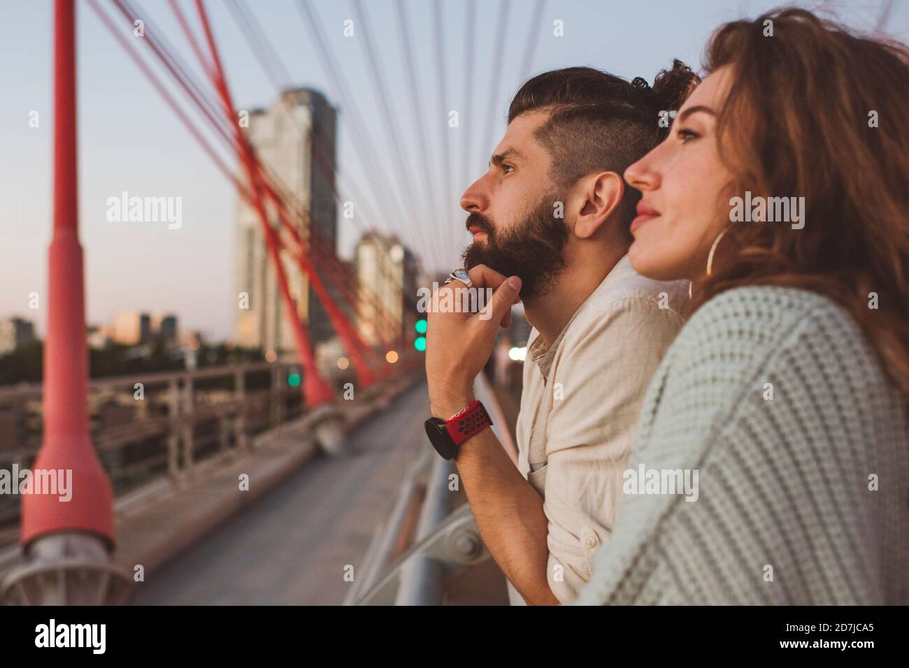Una coppia premurosa che guarda via mentre si trova sul ponte in città Foto Stock
