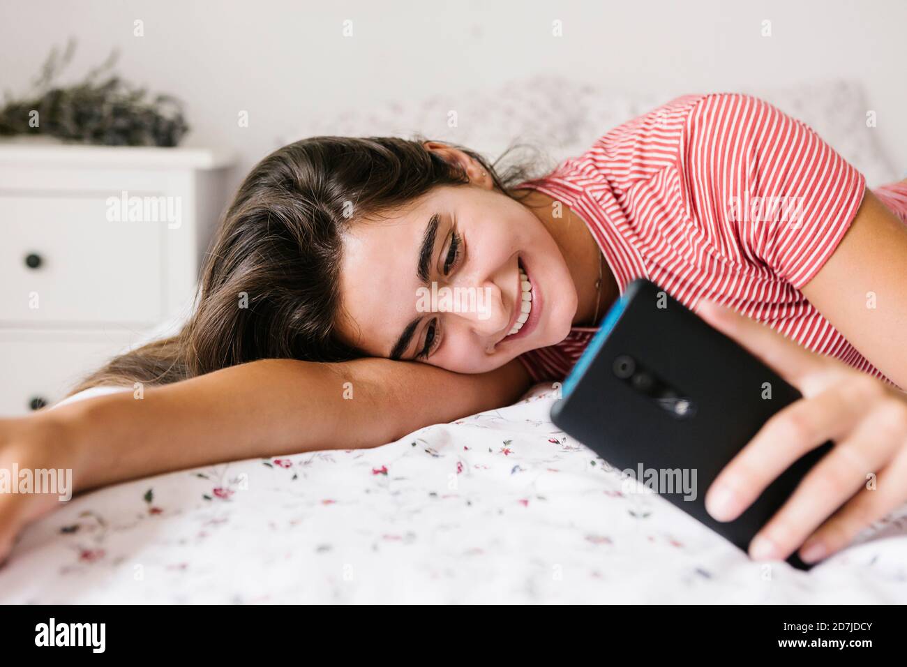 Messaggi di testo sorridenti per le giovani donne sullo smartphone Foto Stock