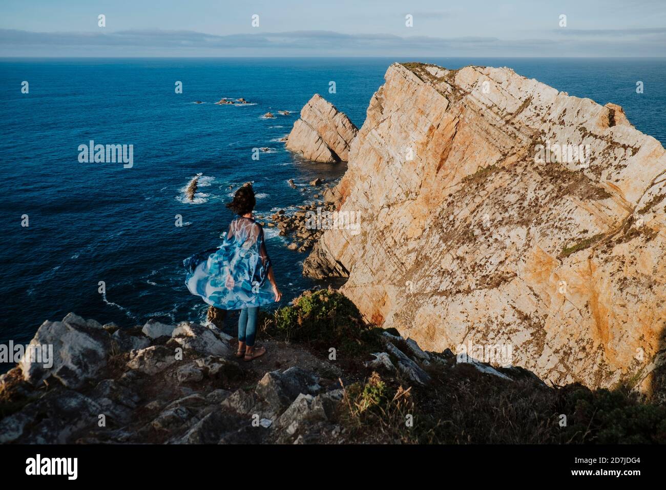 Donna mid adulta in piedi sulla roccia mentre si guarda il mare durante le vacanze Foto Stock