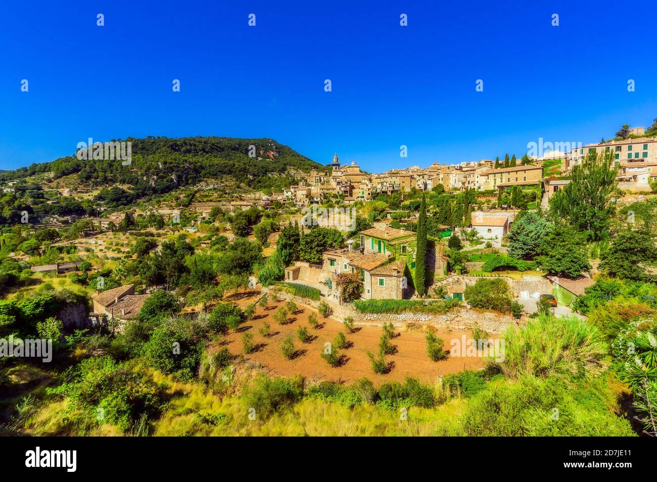Edifici e alberi contro il cielo azzurro durante la giornata di sole a Valldemossa, Maiorca, Spagna, Europa Foto Stock