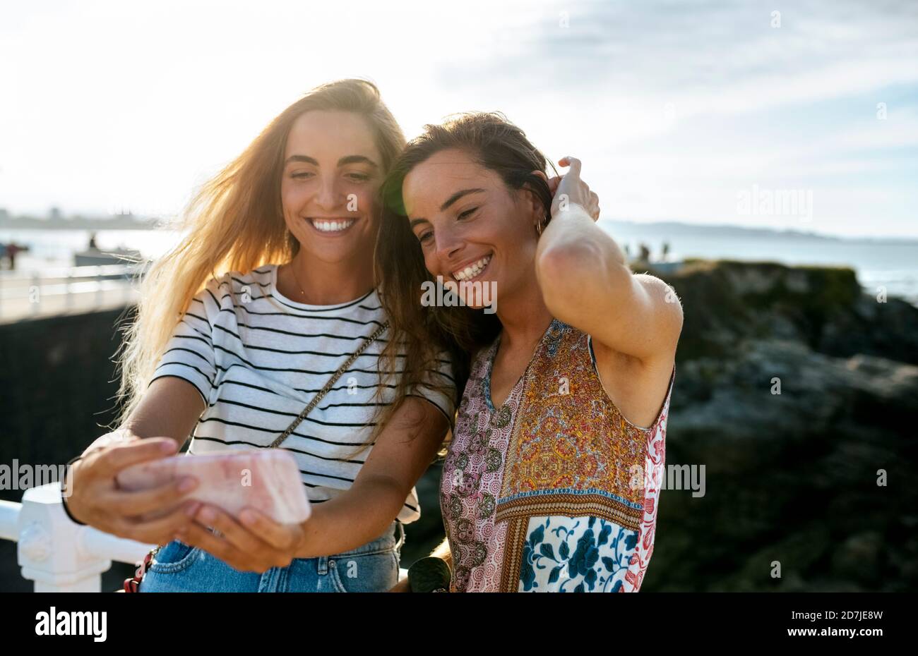 Sorridi giovani sorelle che prendono selfie in spiaggia durante il fine settimana Foto Stock