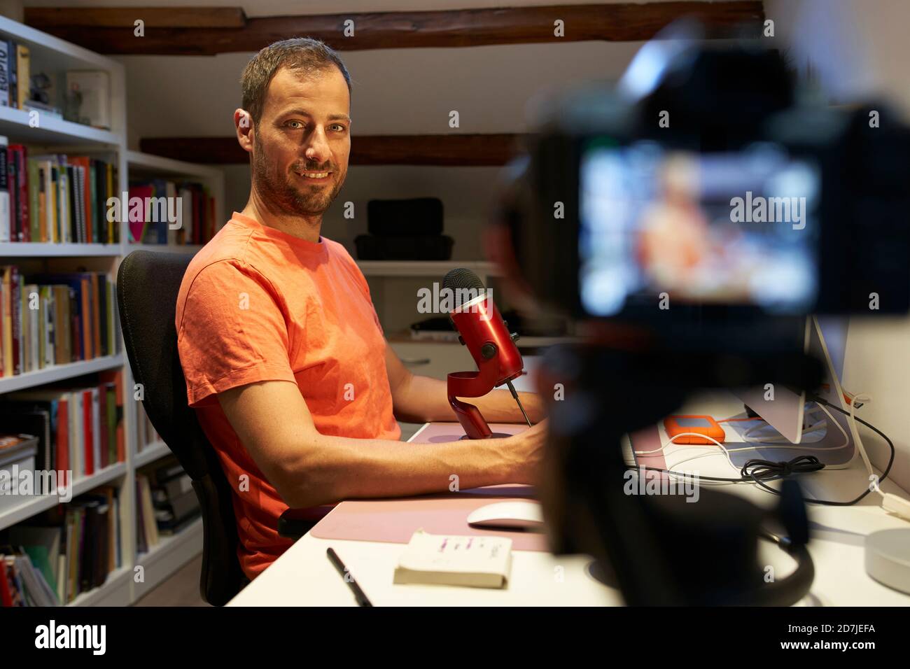 Uomo medio adulto con microfono durante la registrazione di video tutorial da casa Foto Stock