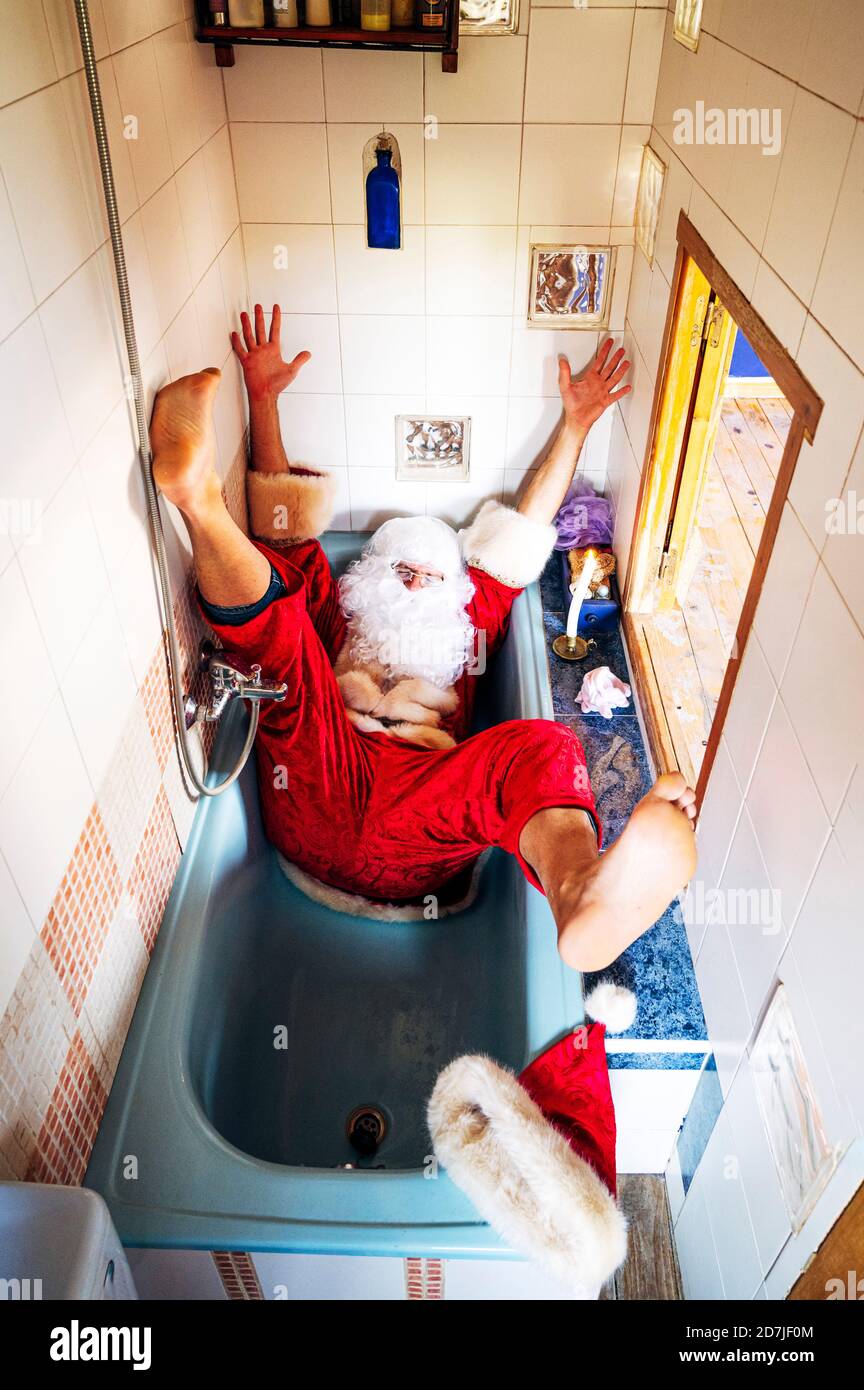 Uomo che indossa il costume di Babbo Natale che cade nella vasca da bagno a casa Foto Stock