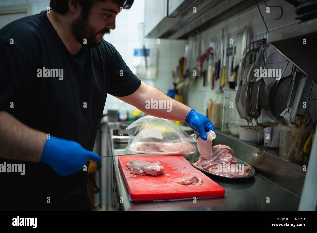 Chef che taglia la carne sul tagliere mentre si è in piedi a commerciale cucina Foto Stock