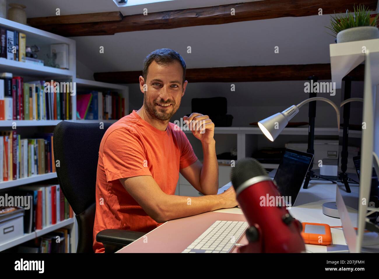 Uomo sorridente che lavora su un computer portatile mentre è seduto a casa Foto Stock
