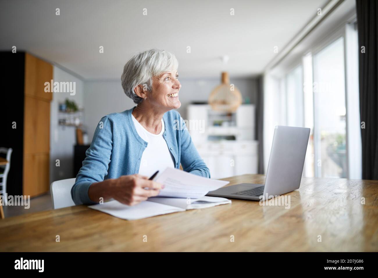 Donna anziana attiva che fa lavoro di carta mentre si siede a casa Foto Stock