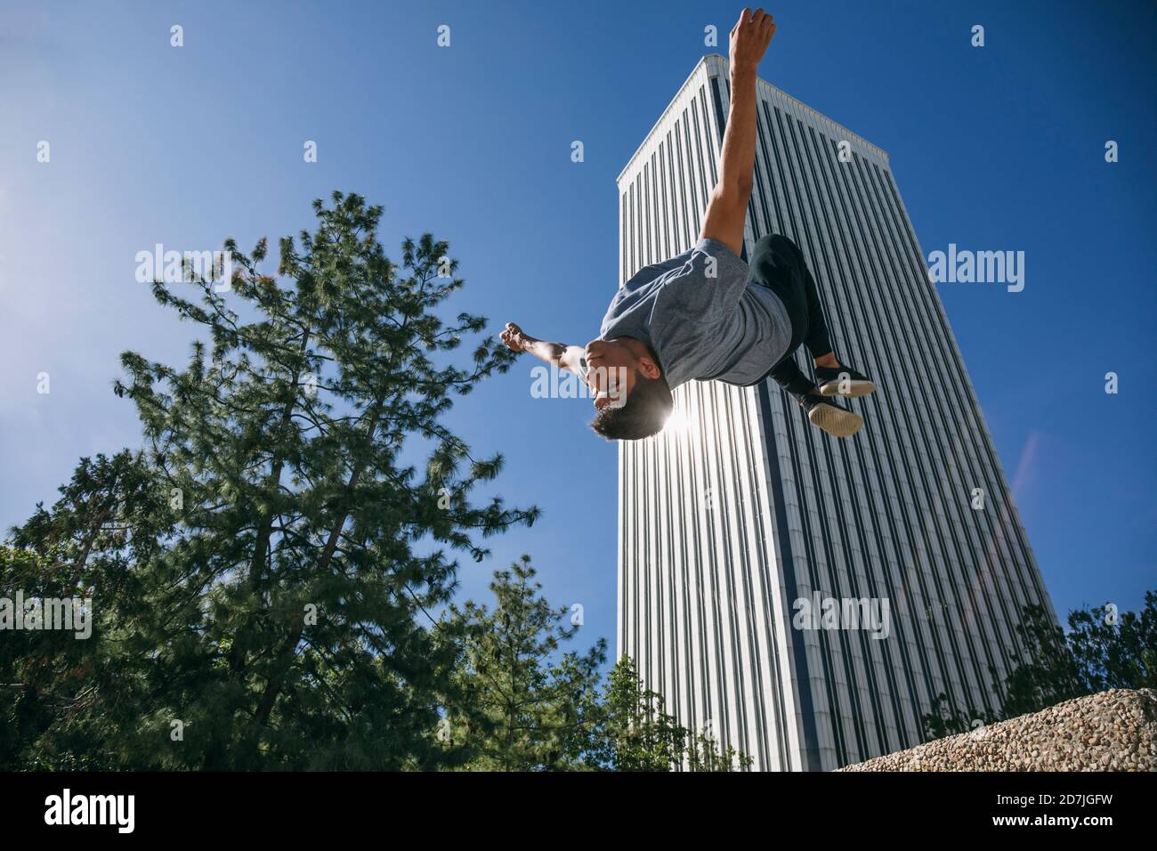 Giovane uomo che salta mentre si esibisce in parkour contro Torre Picasso in città Foto Stock