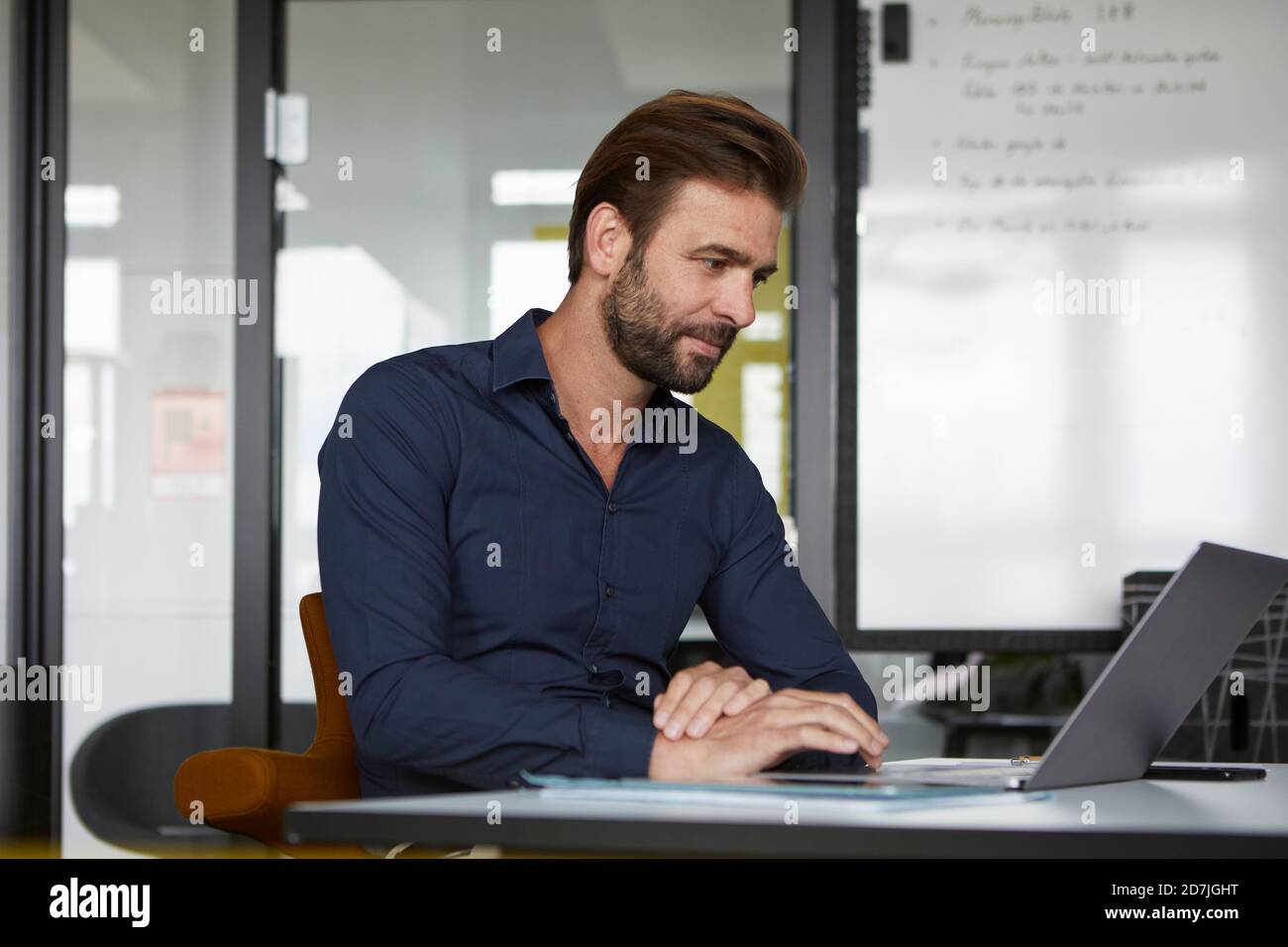 Uomo che lavora su un computer portatile mentre è seduto in ufficio Foto Stock
