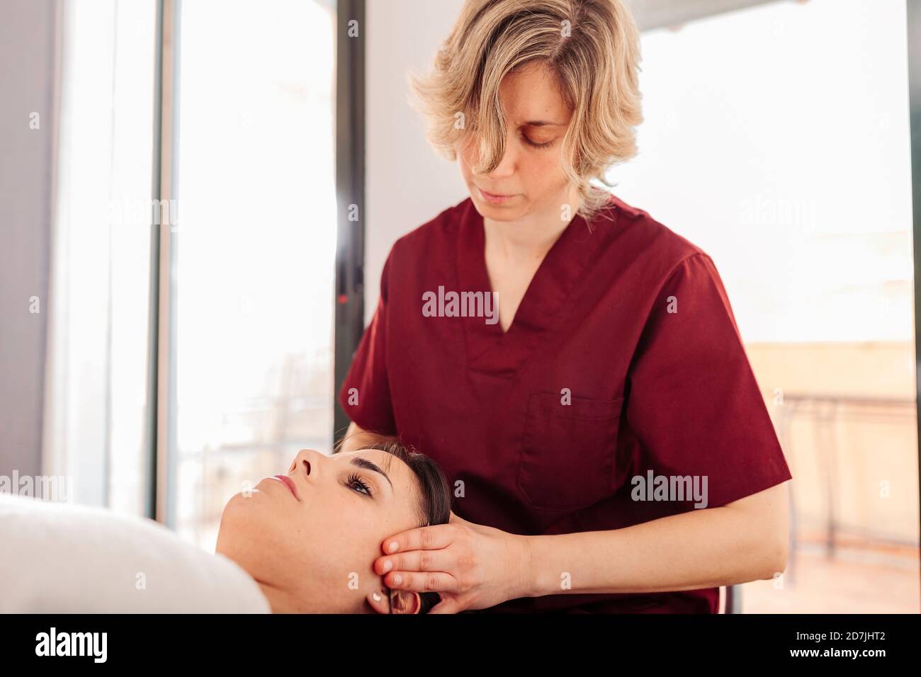 Fisioterapista massaggiare la testa della donna Foto Stock