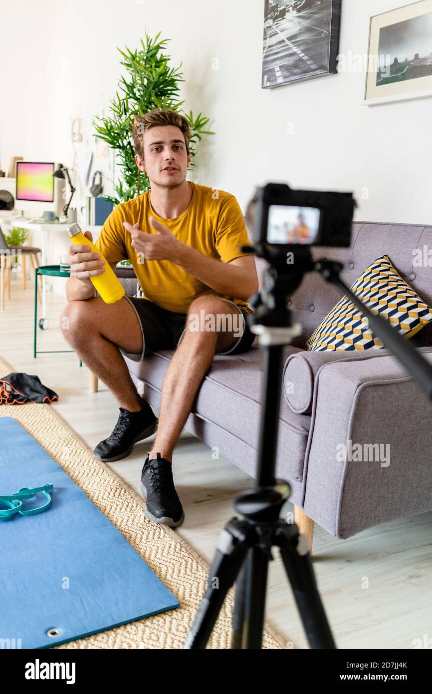 Fitness Trainer che registra una sessione di fitness sulla fotocamera mentre si è seduti divano a casa Foto Stock