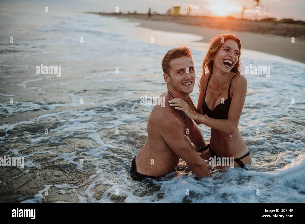 Felice coppia godendosi in acqua alla spiaggia Foto Stock