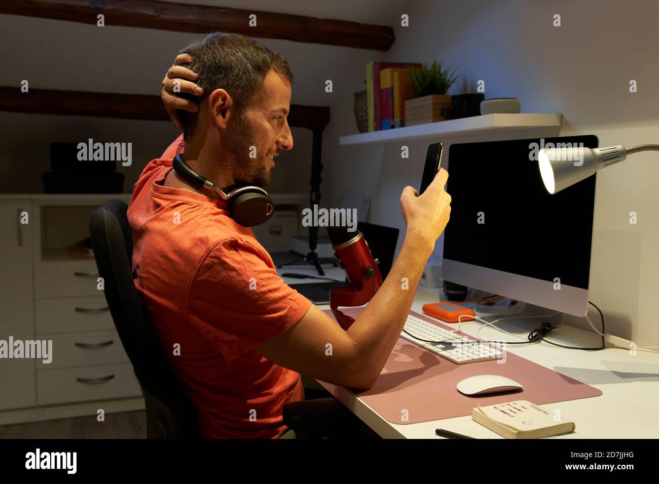 Uomo con messaggi di testo in cuffia sullo smartphone durante il lavoro da casa Foto Stock