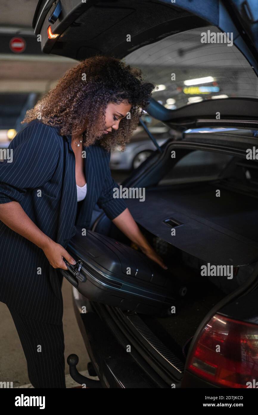 Donna che tiene la valigia all'interno del bagagliaio dell'auto Foto Stock