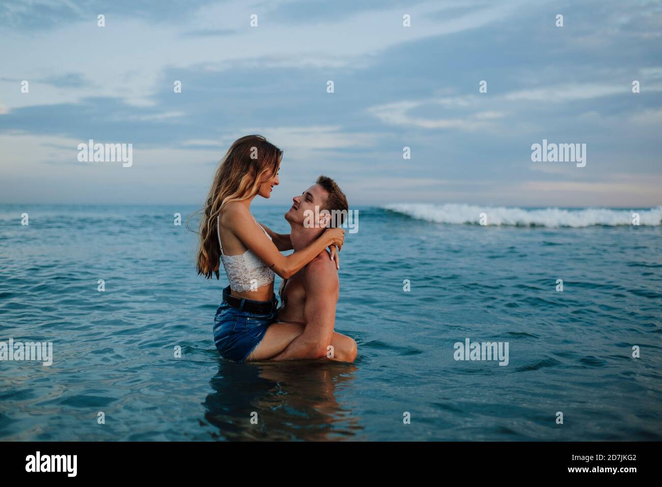 Fidanzato che porta la fidanzata mentre si trova in acqua sulla spiaggia Foto Stock