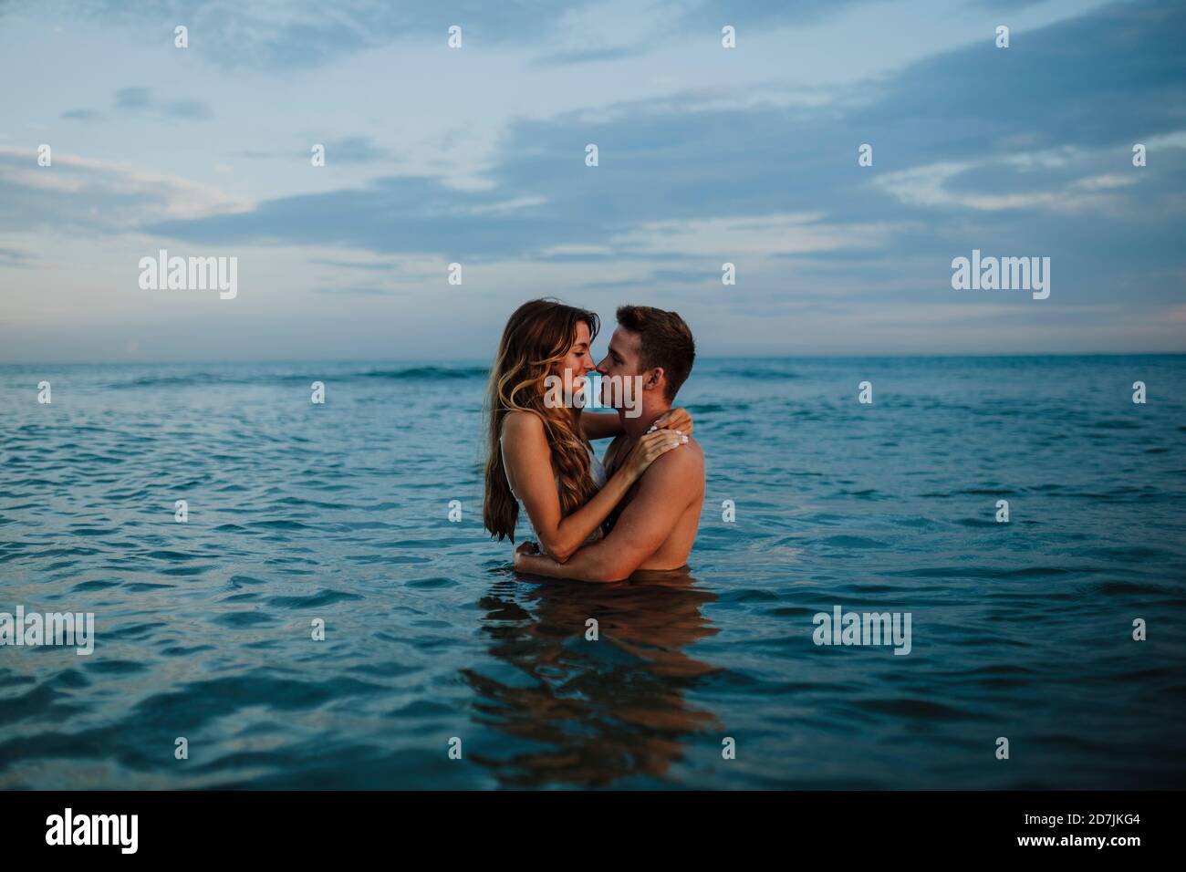 Coppia che fa romanticismo mentre si è in piedi in acqua alla spiaggia Foto Stock