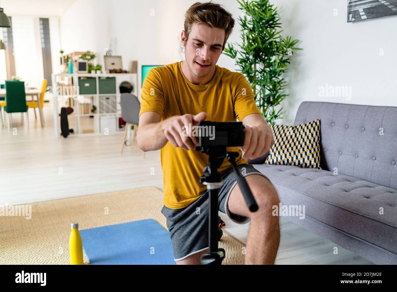 Fitness Trainer regolazione della fotocamera mentre si inginocchiano a casa Foto Stock