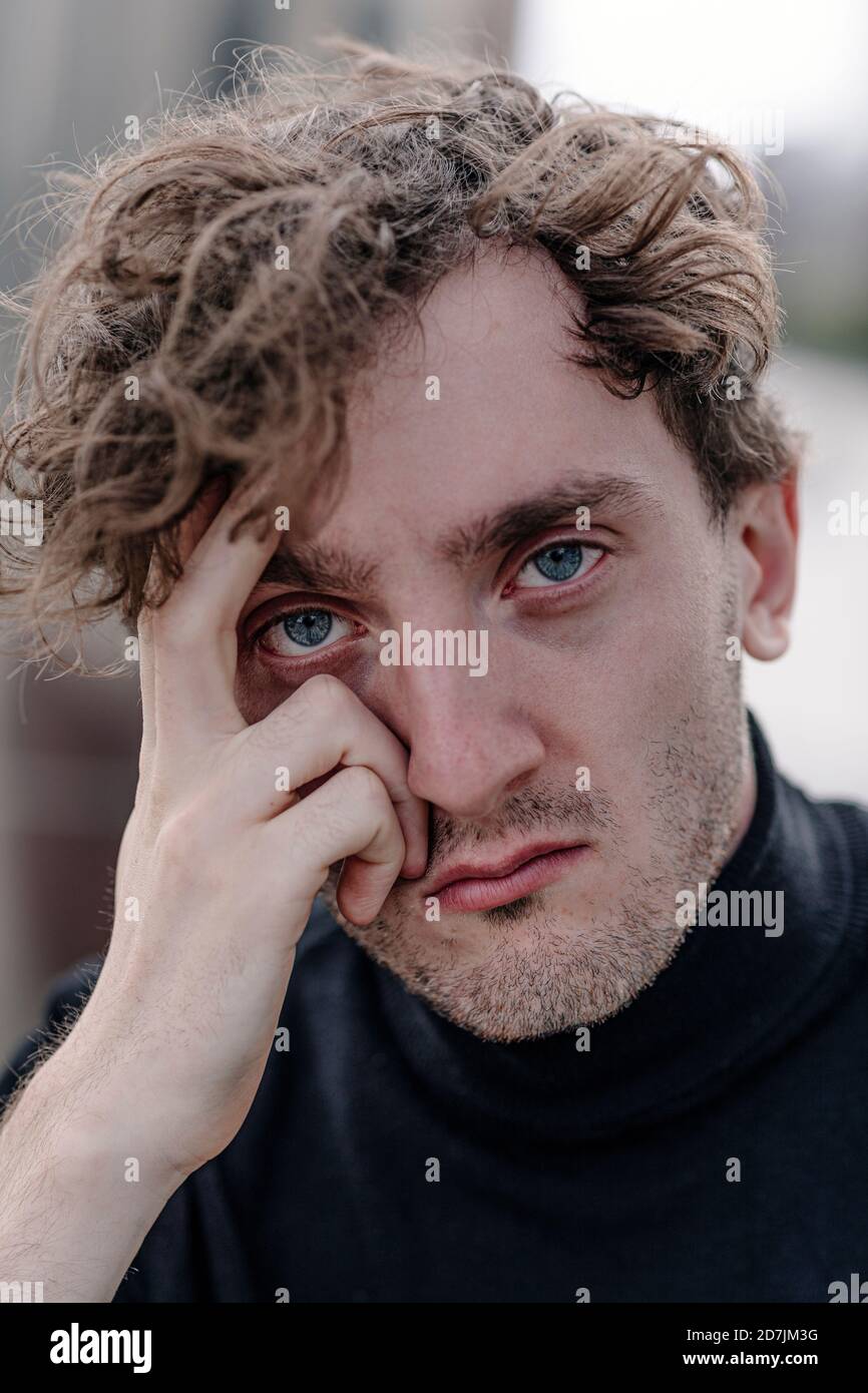 Primo piano ritratto del triste giovane uomo con testa in mano Foto Stock