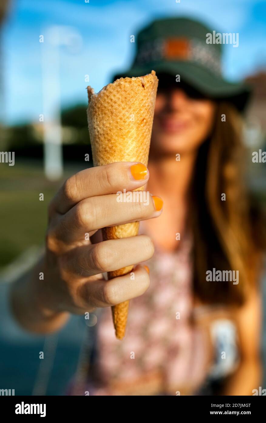 Giovane donna che mostra il cono del gelato mentre si passa il tempo libero città durante il fine settimana Foto Stock