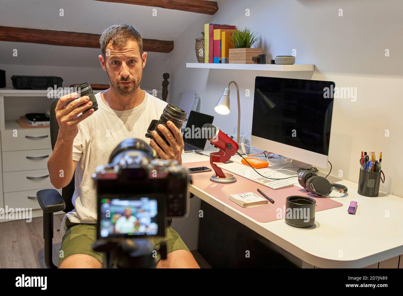 Uomo medio adulto che tiene gli obiettivi della macchina fotografica mentre si siede a casa Foto Stock