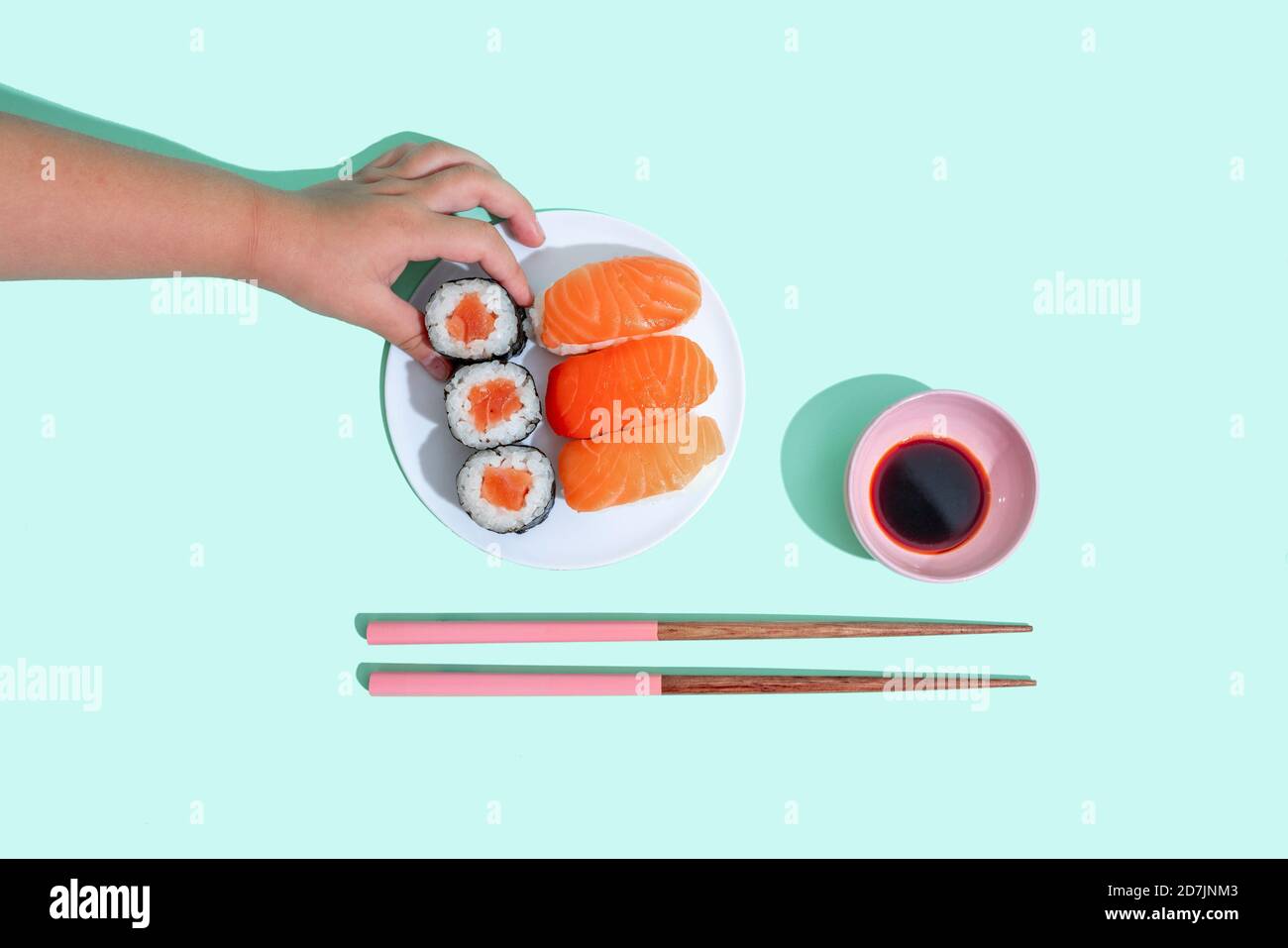 Mano di bambina che raccoglie pezzo di sushi maki Foto Stock