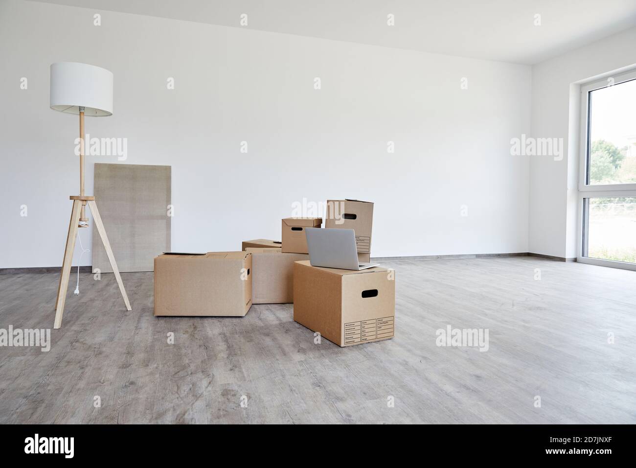 Interno di una camera moderna con scatole di cartone, lampada elettrica e computer portatile Foto Stock