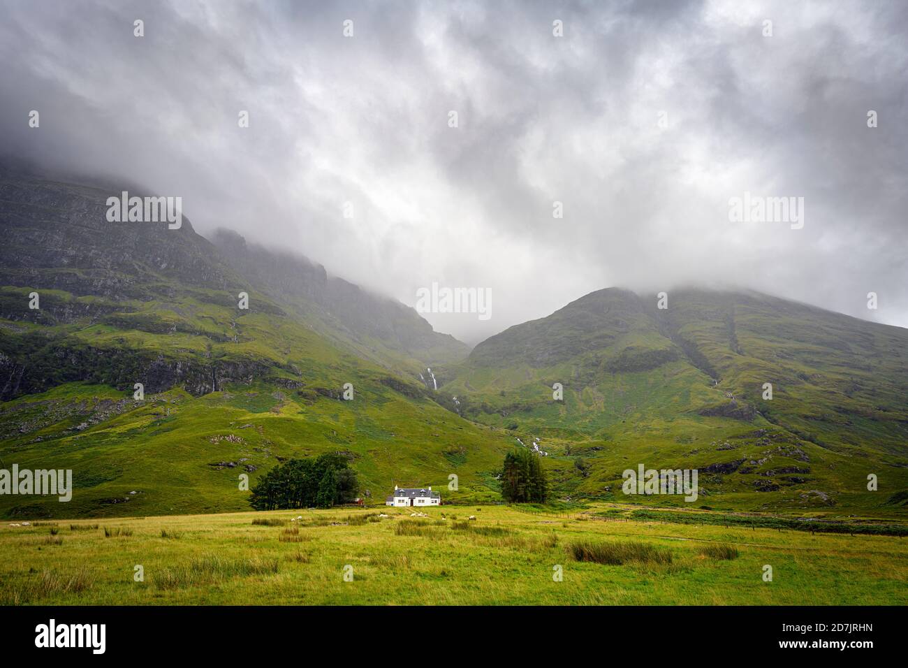 Nuvole grigie su Glen Coe con la casa solita in piedi piede di montagna in background Foto Stock