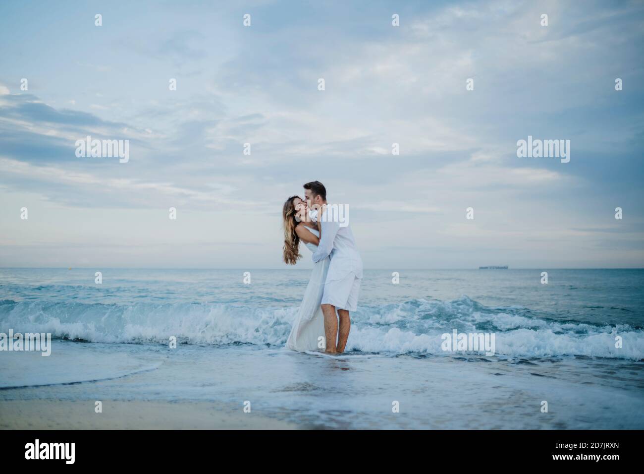 Giovane uomo che baciava la donna mentre si trova in acqua in spiaggia Foto Stock