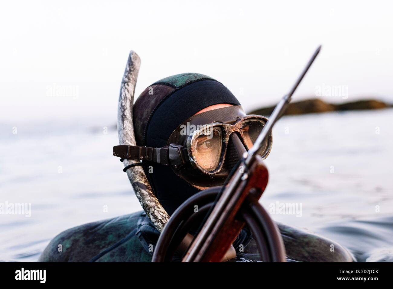 Primo piano di un uomo maturo che indossa una maschera subacquea con un bagno di arpione in mare Foto Stock