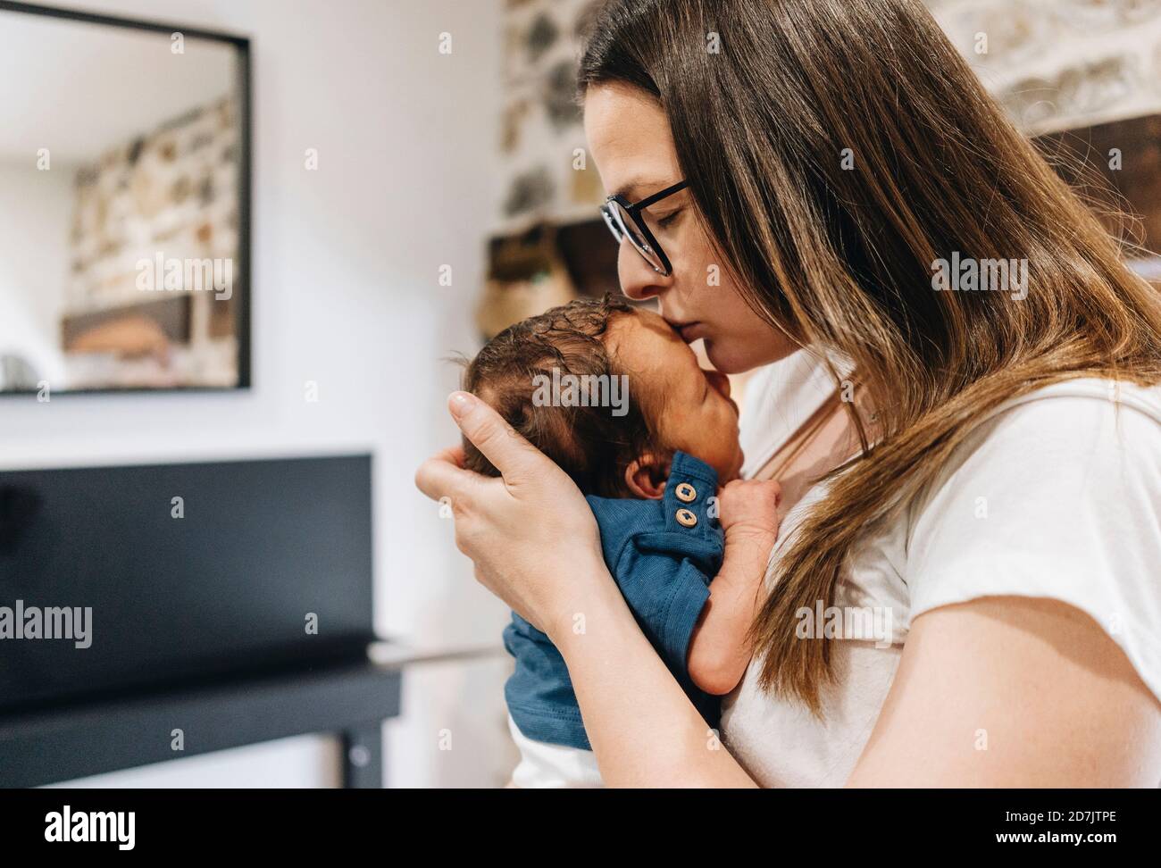 Madre che baciano il bambino sulla fronte Foto Stock