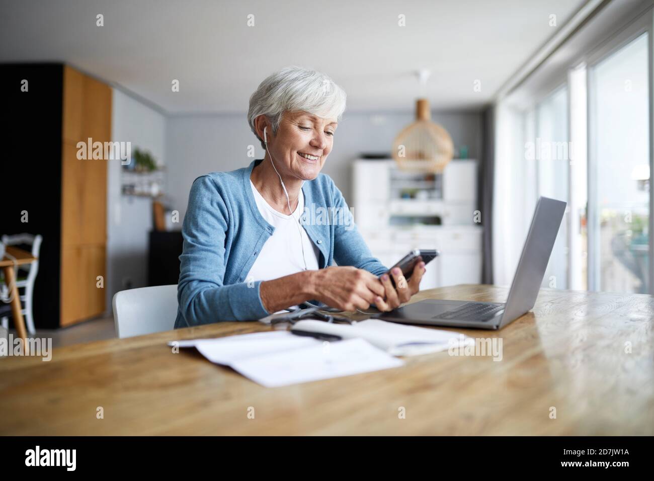 Donna anziana attiva che ascolta la musica mentre si siede a casa Foto Stock