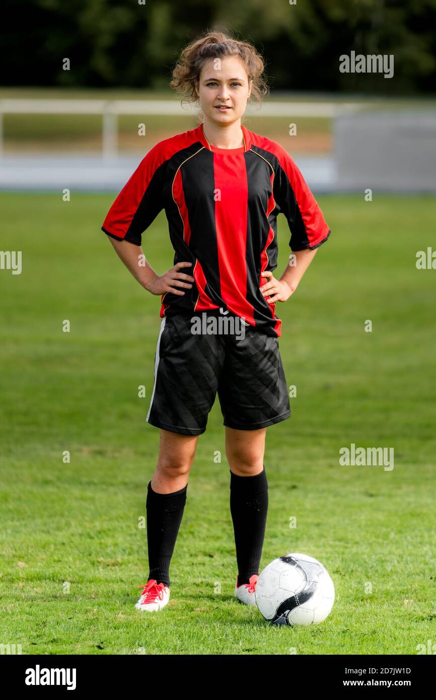 Giocatore femminile con pallone da calcio in piedi sul campo Foto Stock