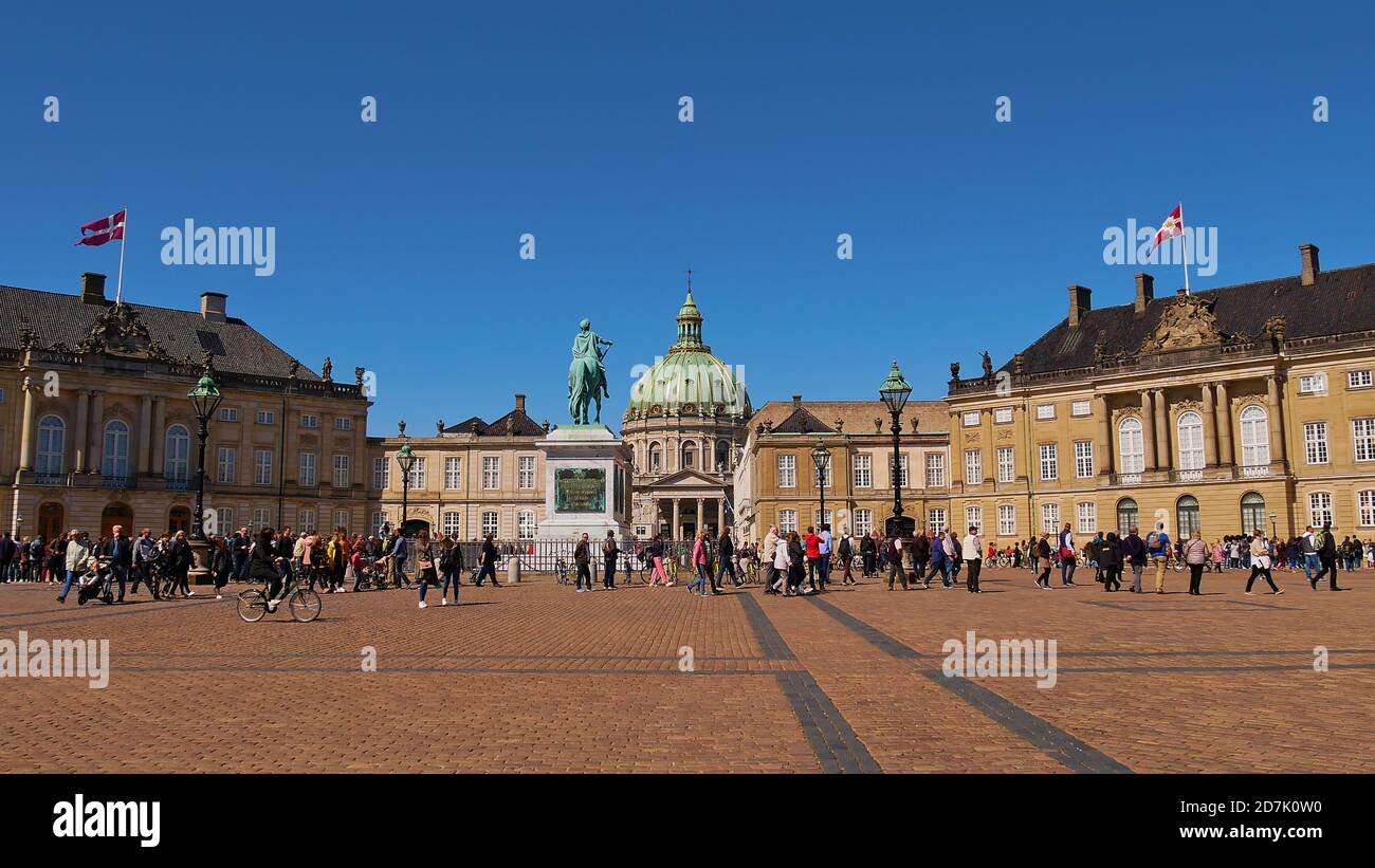 Copenhagen, Danimarca - 04/29/2019: Turisti sulla piazza con statua equestre di fronte al castello reale di Amalienborg con la chiesa Frederiks Kirke. Foto Stock