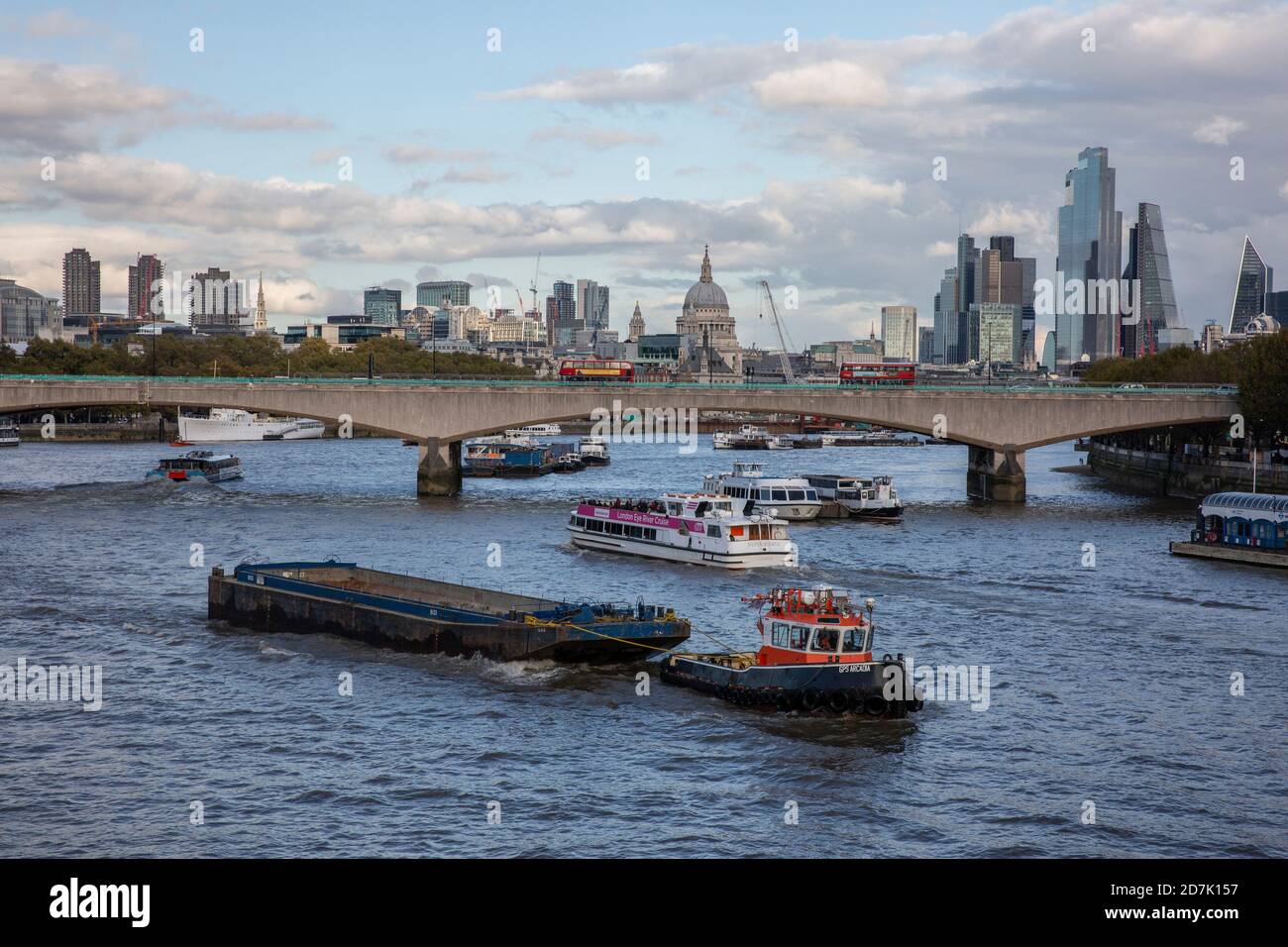 Chiatte trainate da un rimorchiatore sul Tamigi con la Cattedrale di St Paul e la Citta' di Londra nella distanza oltre il Ponte di Waterloo, Inghilterra, Regno Unito Foto Stock