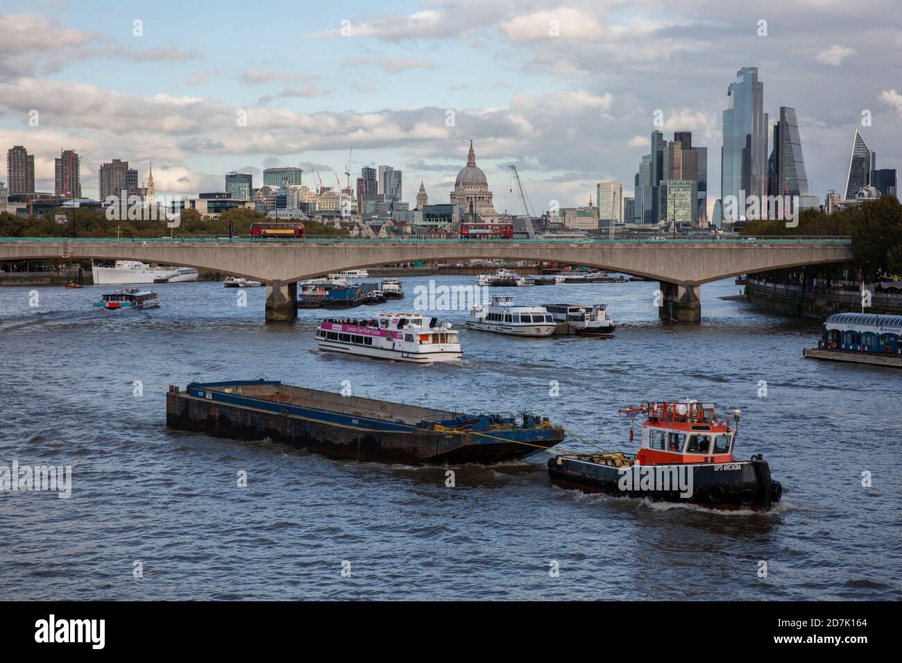Chiatte trainate da un rimorchiatore sul Tamigi con la Cattedrale di St Paul e la Citta' di Londra nella distanza oltre il Ponte di Waterloo, Inghilterra, Regno Unito Foto Stock