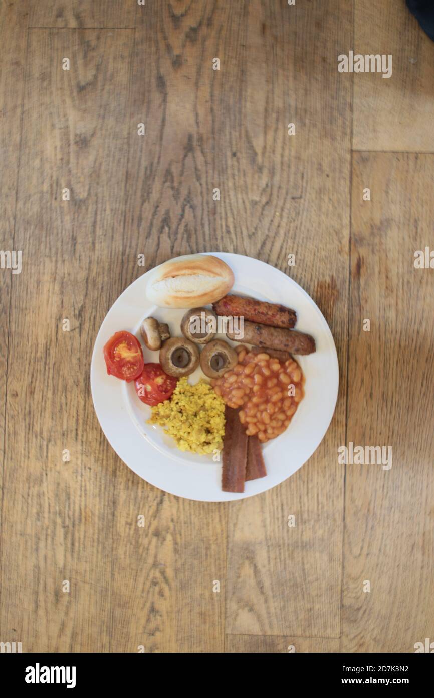 Primo piano vegan colazione latteria carne libera delizioso inglese completo vegetariano tofu spezie scramble mock uovo, piantine pancetta salsicce pomodori funghi, fagioli Foto Stock
