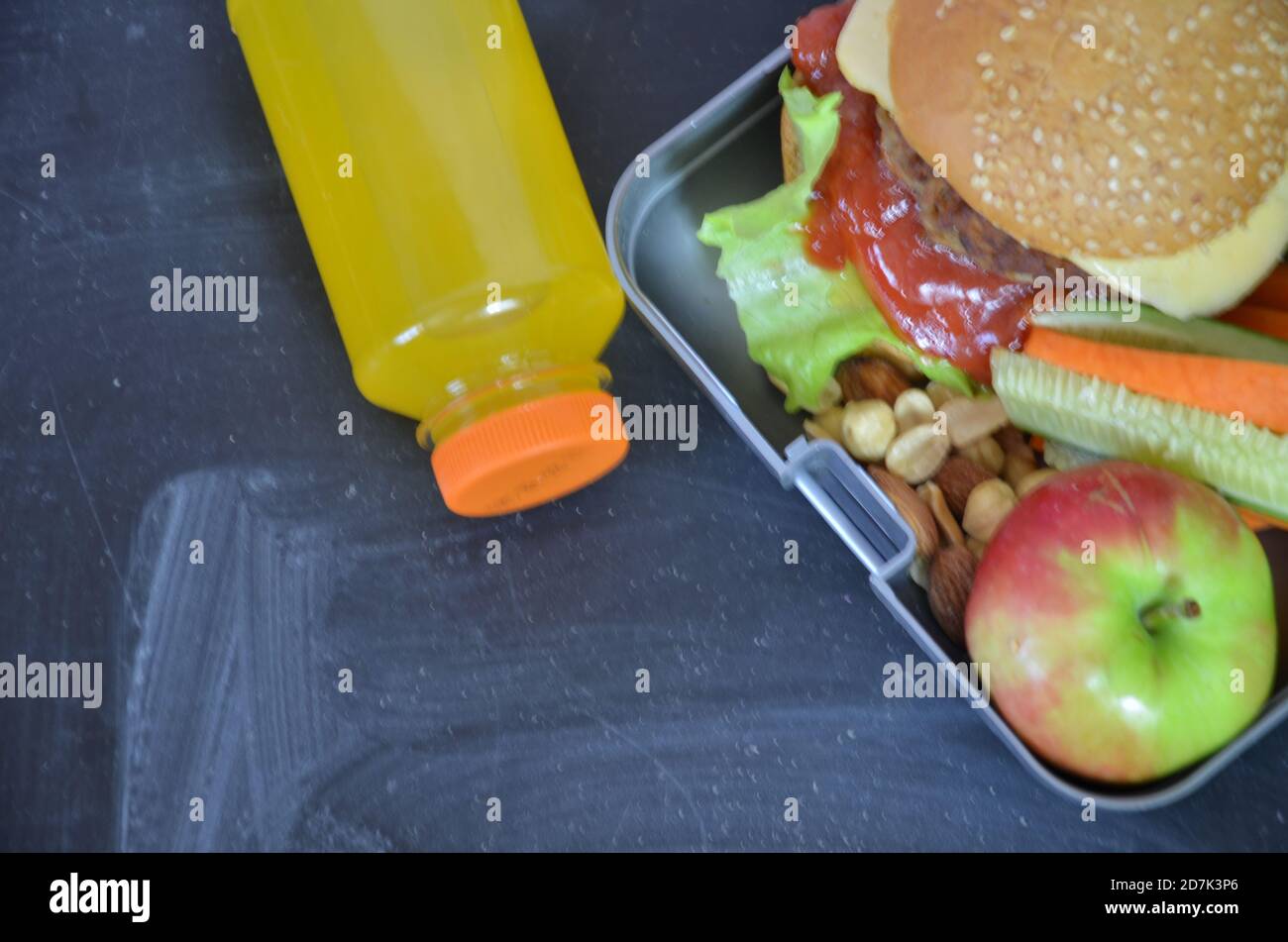 Hamburger fatti in casa con lattuga in scatola. Con succo d'arancia. Noci di banana. Carote di verdure e cetrioli. Sulla lavagna nera della scuola. Snack Foto Stock