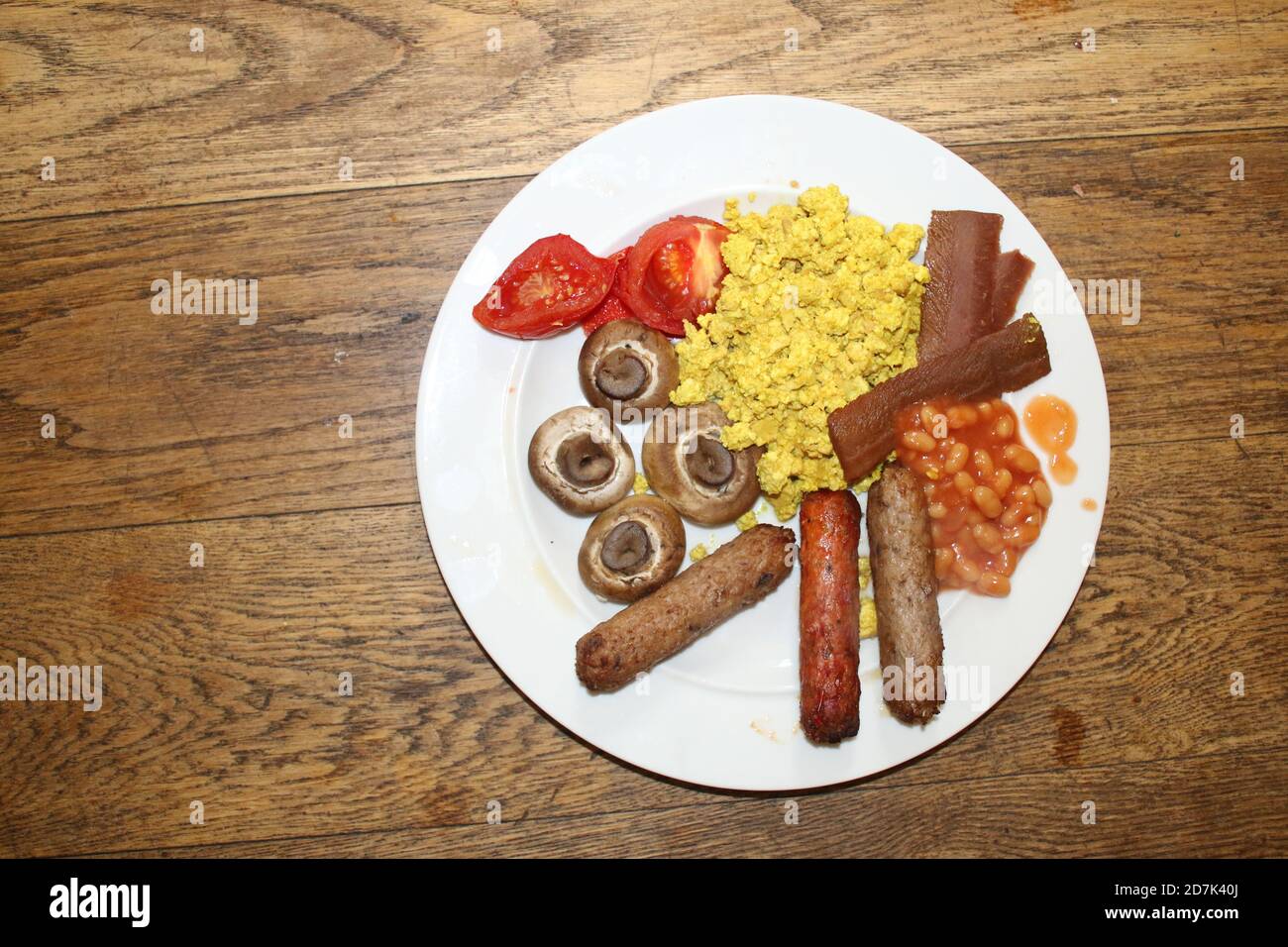 Primo piano vegan colazione latteria carne libera delizioso inglese completo vegetariano tofu spezie scramble mock uovo, piantine pancetta salsicce pomodori funghi, fagioli Foto Stock