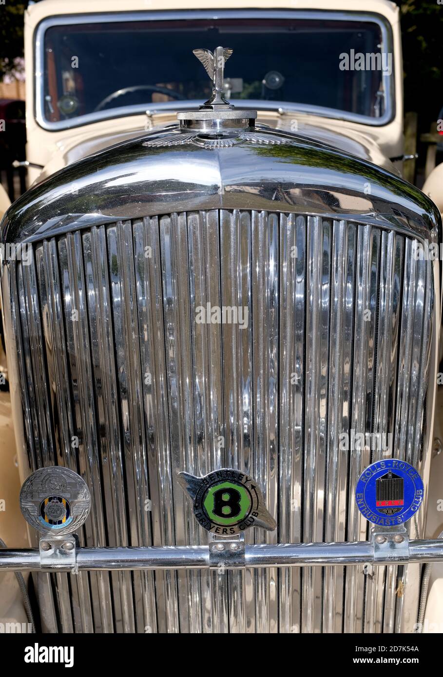 Primo piano della griglia del radiatore cromata per auto Bentley degli anni '30 con fari, mascotte e barra del logo contro la carrozzeria color crema per auto. Condizione di atrio. Foto Stock