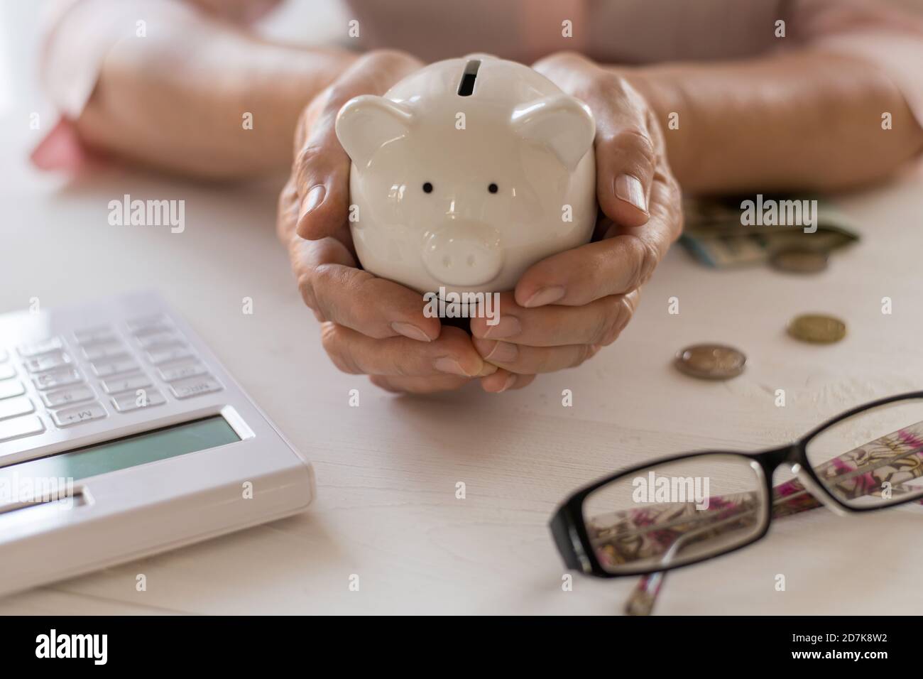 Le mani delle donne anziane tengono in una banca del piggy della mano, il concetto di pensione, di risparmio, di risparmio, di età anziano. Foto Stock