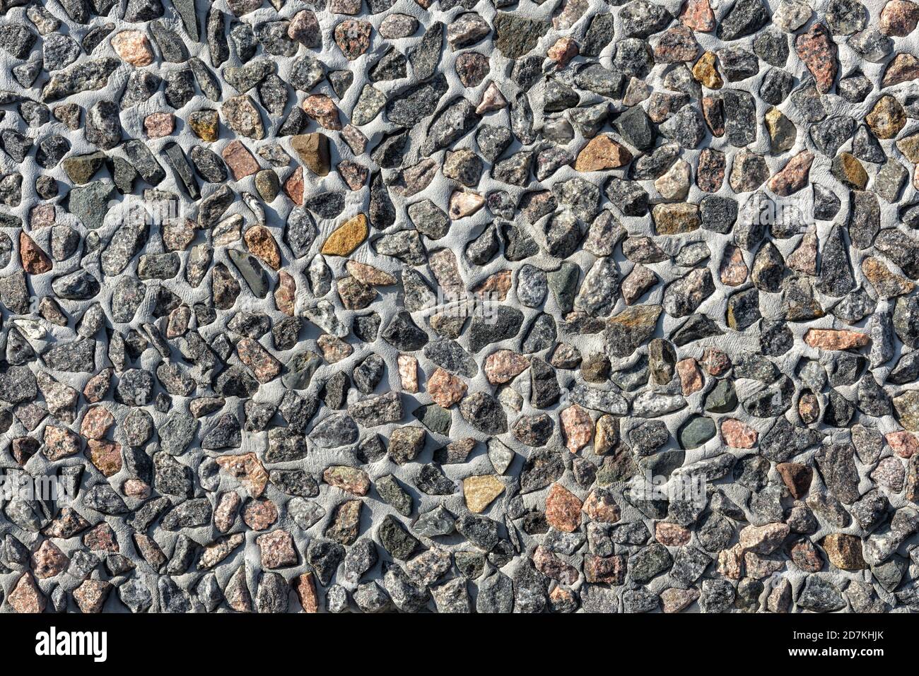 Parete decorata lotto di pietre piccole, sfondo astratto texture. Molte pietre di granito in cemento o in cemento, modello su exterio edificio moderno Foto Stock