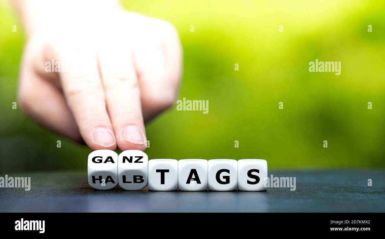 La mano trasforma i dadi e cambia l'espressione tedesca 'halztag' (part time) in 'ganztags' (full time). Foto Stock