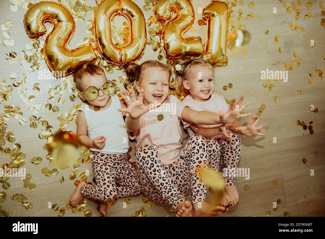 Bambini, 3 sorelle, festeggiano il nuovo anno 2021 a casa, ridendo in confetti Foto Stock