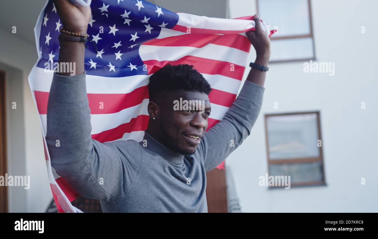 Uomo nero afroamericano con bandiera USA sul balcone. Foto di alta qualità Foto Stock