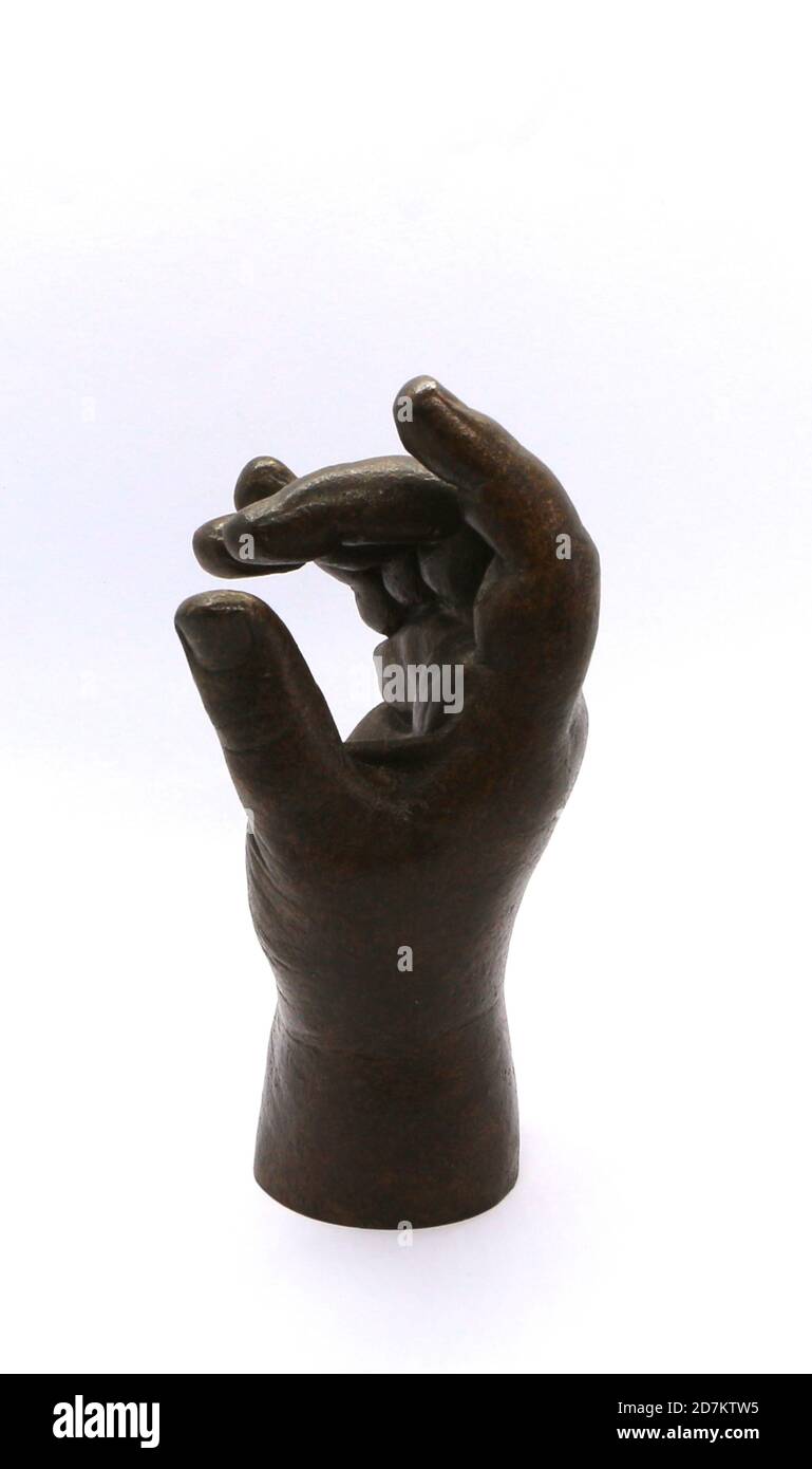 Foto di una scultura a mano del bambino in bronzo e fortemente illuminata su sfondo bianco Foto Stock