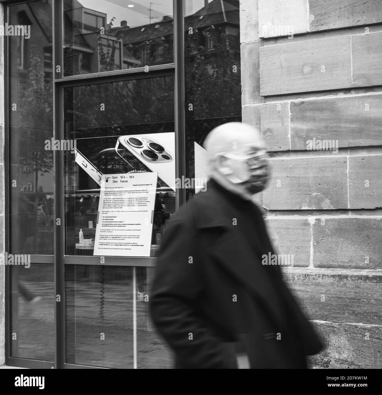 Parigi, Francia - 23 ottobre 2020: Immagine quadrata in bianco e nero dell'uomo con maschera chirurgica davanti all'Apple Store mentre il nuovo iPhone 12 e iPhone 12 Pro sono in mostra durante il giorno del lancio in Apple Store Foto Stock